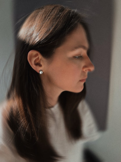 Woman with long dark hair wearing a white top against a neutral background, wearing the VEERA earrings